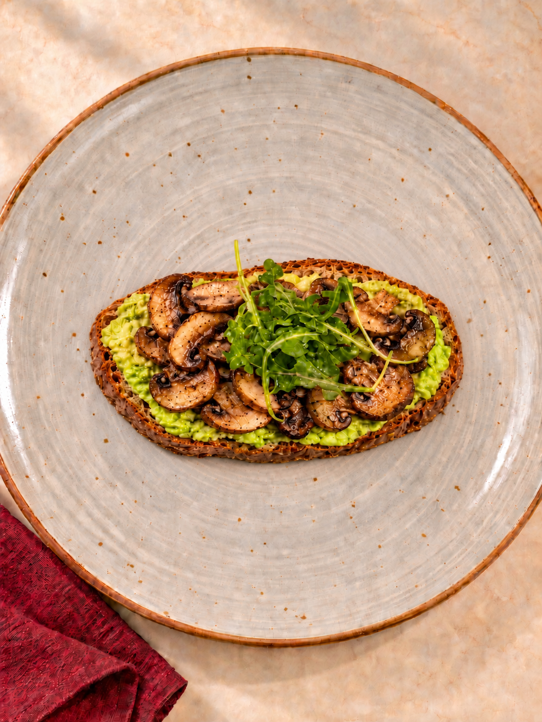 CHEMINÈ Avocado and Mushroom Toast with mashed avocado, sliced mushrooms, and arugula on a ceramic plate